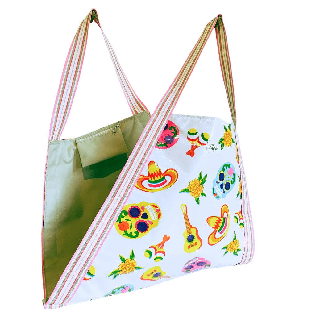 White tote bag with colorful Mexican Day of the Dead skulls, sombreros, maracas, guitar, and flower patterns