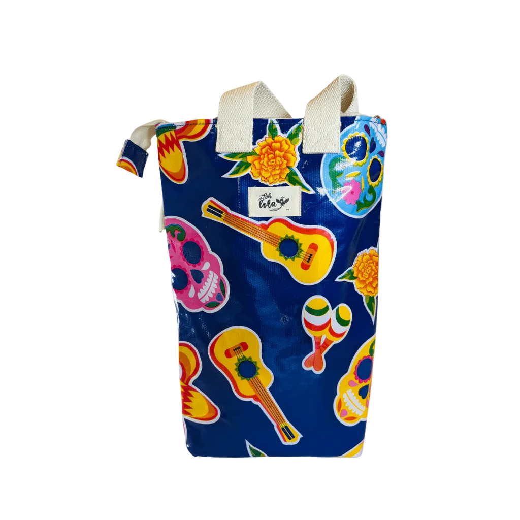 Blue tote bag with colorful guitar, maracas, skulls, and marigold flower print and white handles