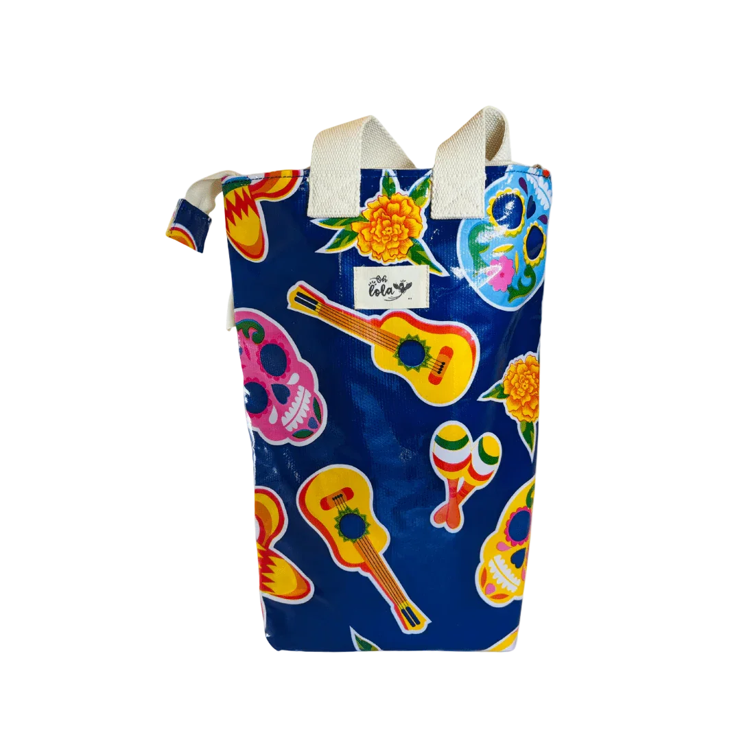Blue tote bag with colorful guitar, maracas, skulls, and marigold flower print and white handles