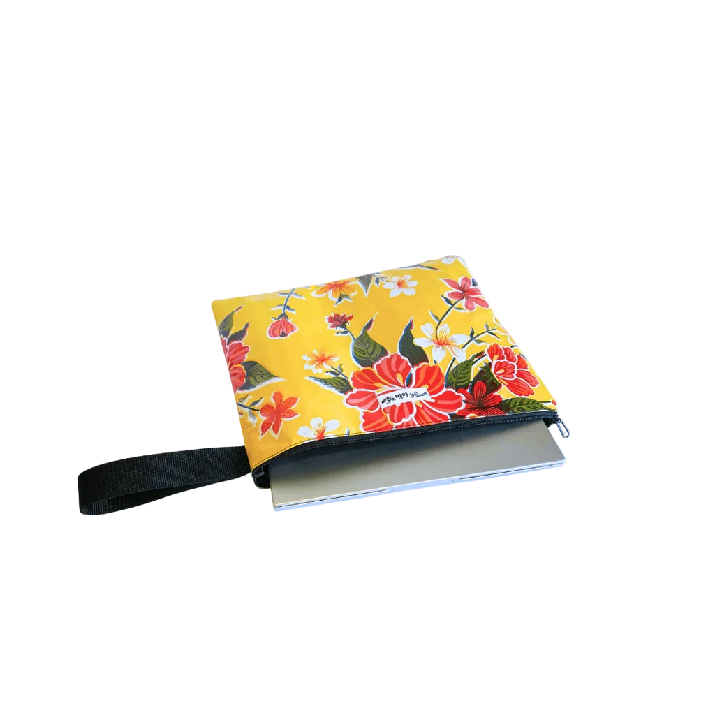 Yellow floral zippered pouch with black handle partially covering a silver laptop